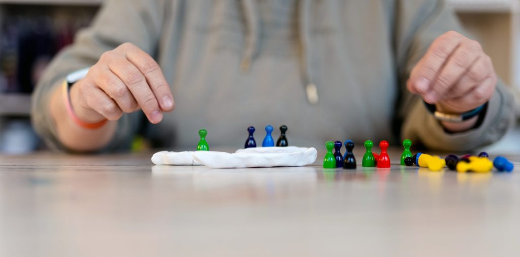 Detailaufnahme von Händen, die kleine bunte Spielfiguren in Gruppen auf einem Tisch anordnen. Symbolbild für systemisches Coaching, Aufstellungen und kreative Prozessbegleitung bei Kerstin Biß in Nürnberg.