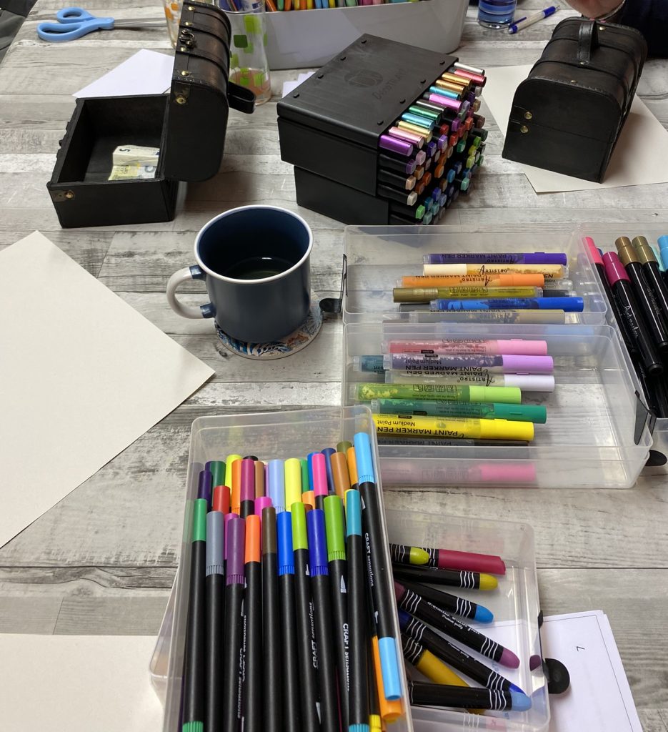 Kreativtisch mit vielen bunten Stiften, Papier und einer Tasse – Raum für kreative Impulse im Workshop