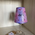 Rosa-violett glänzende Lichtinsel mit Glitzerschmetterlingen, Herzen und dem Spruch:„Glück ist, jemanden wie dich zu haben.“