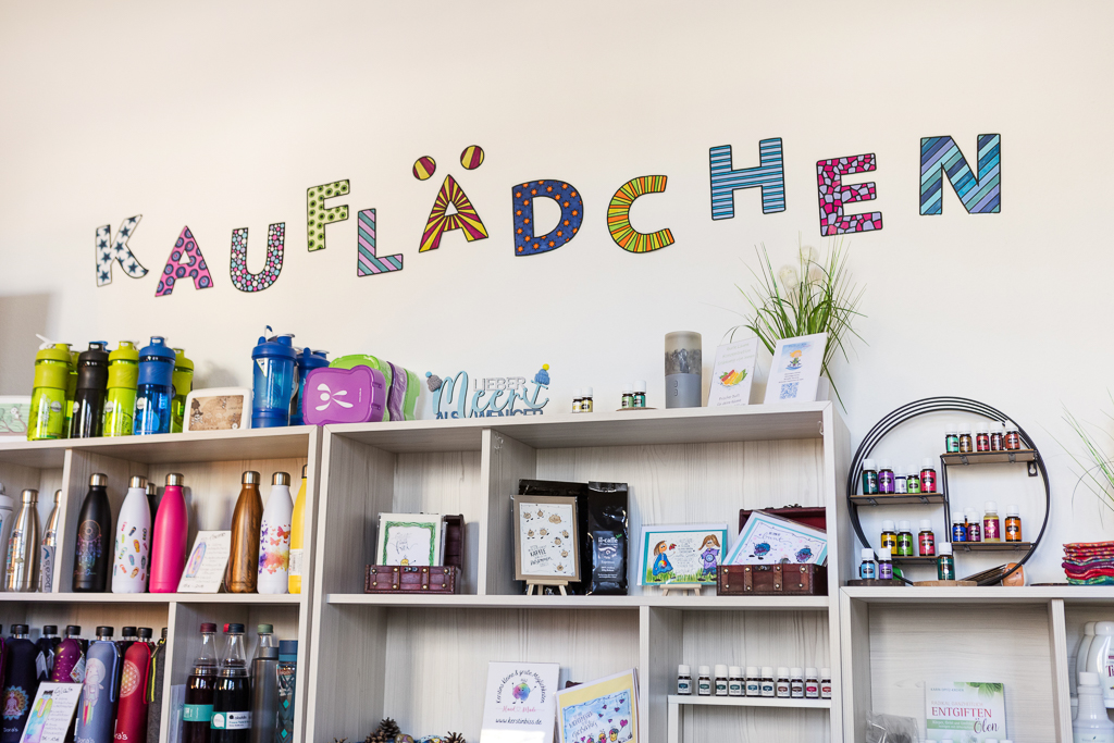 Regalansicht im Kauflädchen mit bunten Flaschen, Ölen und handgemachten Produkten Blick ins Kauflädchen von Kerstin Biß: bunte Buchstaben an der Wand, Regale mit Trinkflaschen, Young Living Ölen, Karten, Kaffee und handgemachten Unikaten
