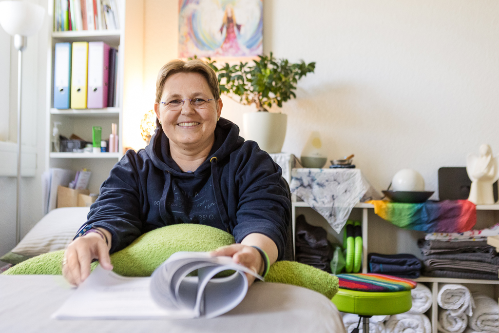 Kerstin Biß im Studio – einladende Atmosphäre bei den Access Bars® Kursen Kerstin Biß sitzt entspannt mit Unterlagen im Praxisraum, bereit für einen Access Bars® Kurs in persönlicher, herzlicher Umgebung