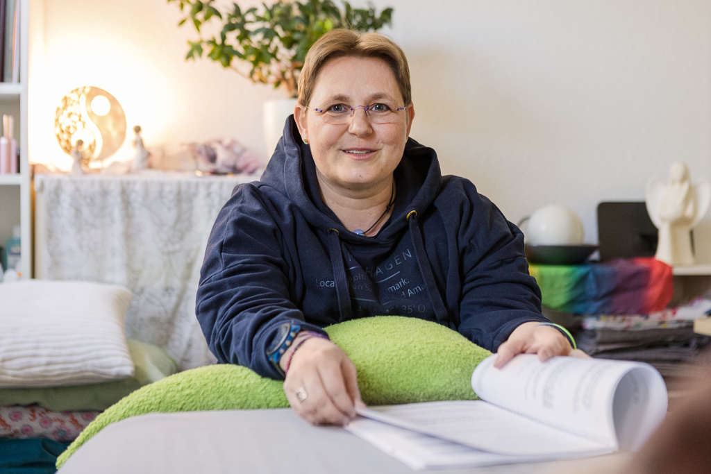 Kerstin Biß im Studio, freundlich und einladend, mit Unterlagen auf dem Schoß – Coaching- & Beratungssituation