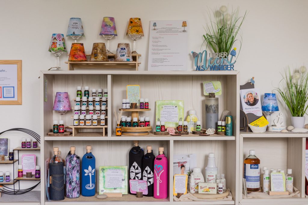 Regal im kleinen Kauflädchen mit handbemalten Weinglaslampen, ätherischen Ölen von Young Living, nachhaltigen Flaschen und Thieves-Produkten.