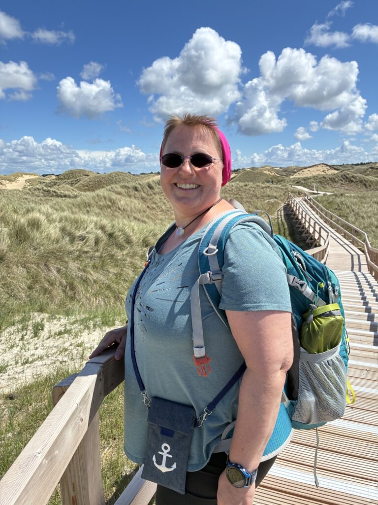 Kerstin Biß auf einem Holzsteg in den Dünen auf Amrum – ein Symbol für ihren persönlichen und beruflichen Weg.