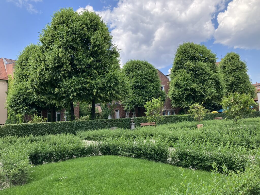Grüne Parkanlage mit Bäumen und Sitzbänken in den Hesperiedengärten