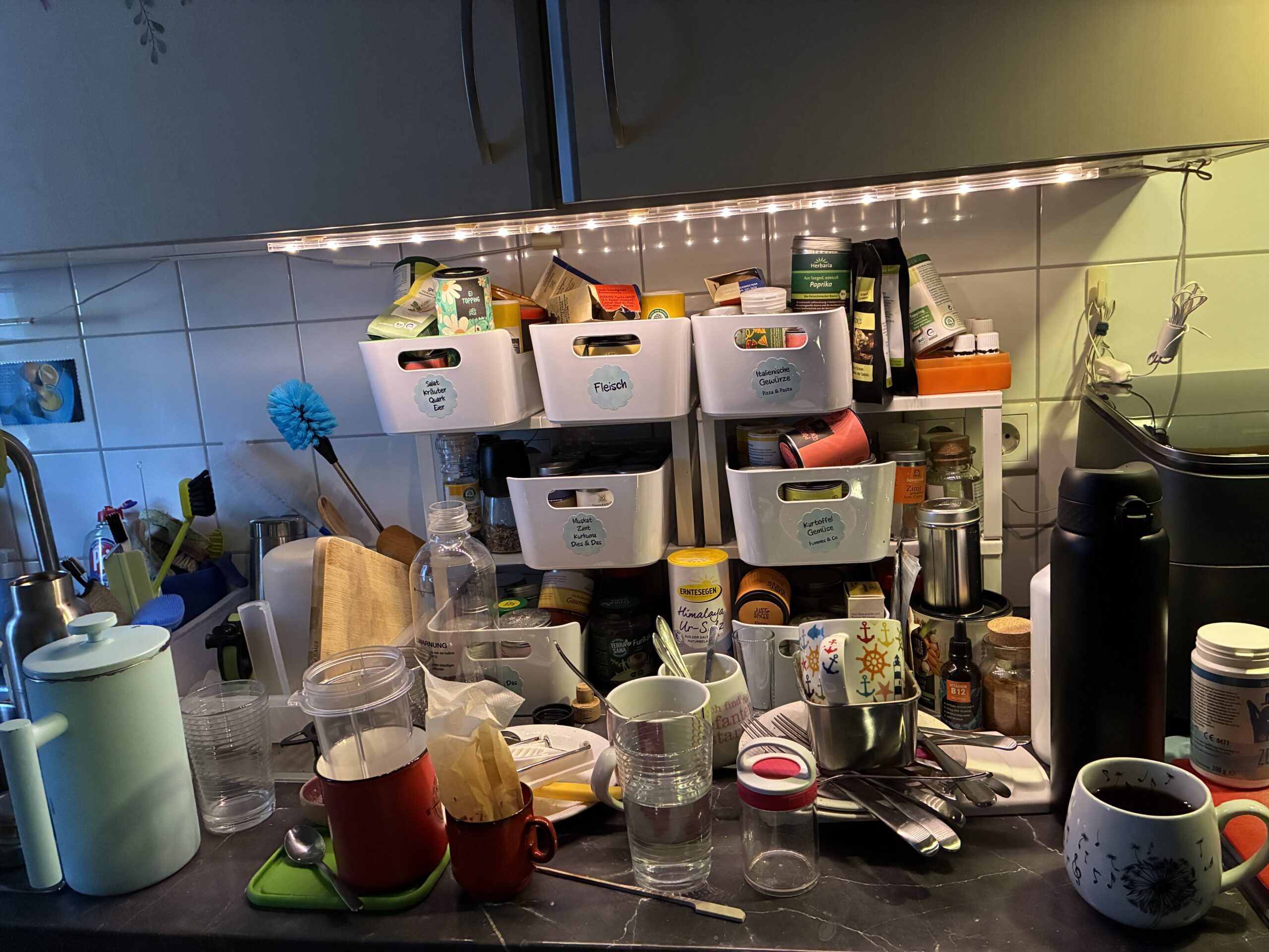 Volle Küchenarbeitsfläche mit Geschirr, Tassen und Küchenutensilien während eines kreativen Schreibtages